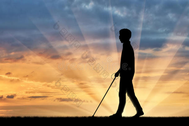 残疾人盲人在日落时用拐杖行走