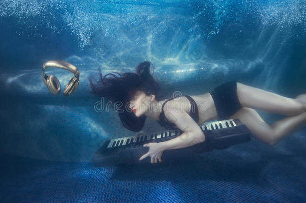 游泳池里的女孩拿着钢琴。