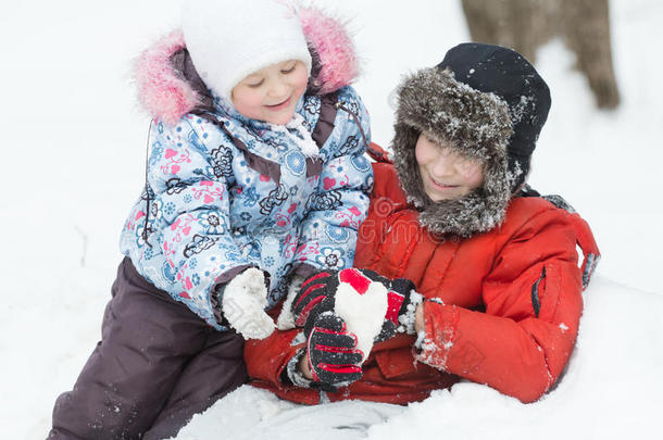 霜冻的户外肖像，两个玩耍的兄弟姐妹在冬天的雪堆里飘着雪的心形人物