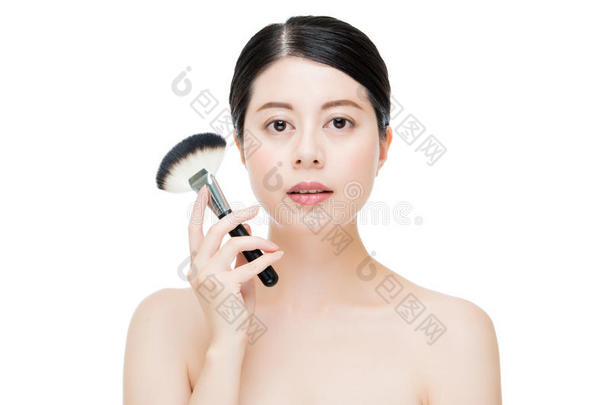 用刷子在美丽的亚洲模特脸上涂上化妆基金会