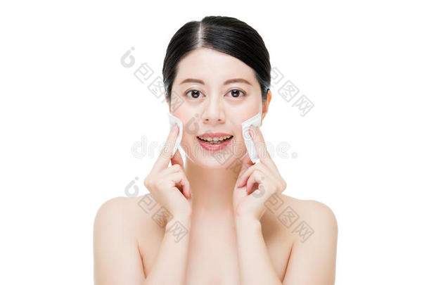 美丽的亚洲女人用棉签从脸上卸妆