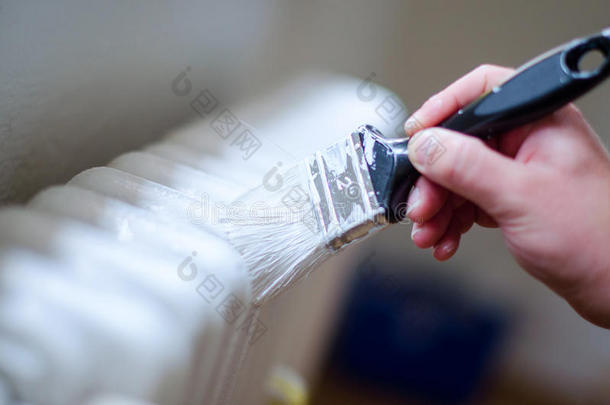 关闭画家手臂，画一个加热散热器与油漆滚筒。 专业工人手拿肮脏的画笔。