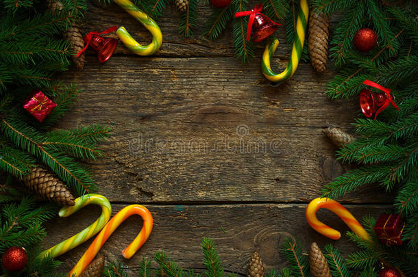 圣诞边界与杉木树枝，锥，圣诞装饰品和糖果拐杖在乡村木板上