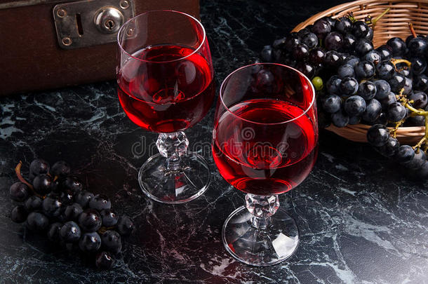 <strong>深色大理石</strong>背景上的一杯红酒。 背景上的一簇蓝色葡萄。。