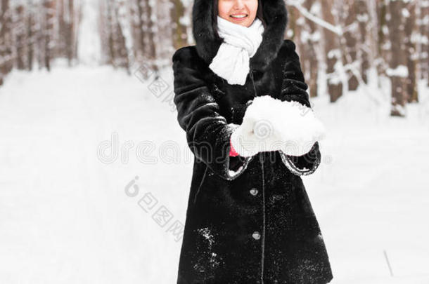 特写女人手里拿着天然柔软的白雪，做一个雪球，在寒冷的冬天微笑着