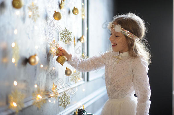 穿着优雅的8-9岁女孩与喜悦接触黄金圣诞花环