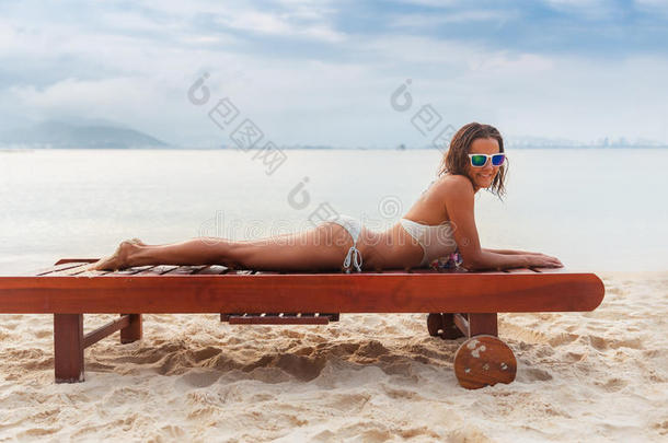 美丽的年轻女人在<strong>海边</strong>的沙滩上<strong>晒太阳</strong>