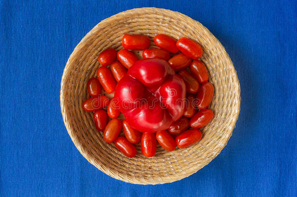 新鲜西红柿，红色辣椒在蓝色背景的篮<strong>子</strong>里