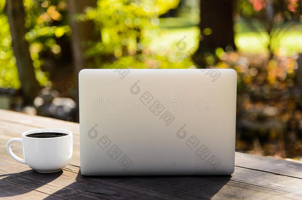 野餐桌上的咖啡杯和<strong>银色笔记本</strong>电脑