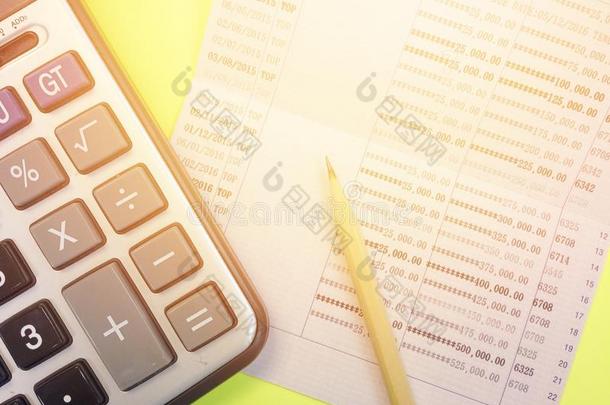 黄色背景上的计算器、铅笔和储蓄账户存折