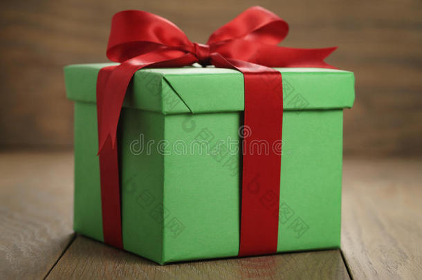 绿色纸礼盒礼品盒，盖子和红色丝带蝴蝶结在木桌上