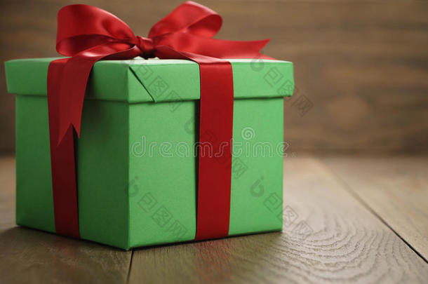 绿色纸<strong>礼盒礼品</strong>盒，盖子和红色丝带蝴蝶结在木桌上，有复制空间