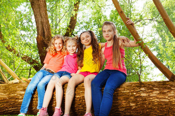 四个可爱的女孩朋友<strong>坐在</strong>倒下的<strong>树上</strong>