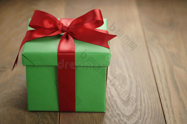 绿色纸礼盒礼品盒，盖子和红色丝带蝴蝶结在木桌上，有复制空间