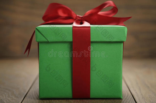 绿色纸礼盒礼品盒，盖子和红色丝带蝴蝶结在木桌上