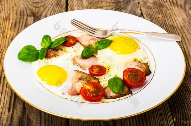 煎鸡蛋加培根和蔬菜在一个白色的盘子里