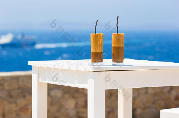 弗雷普，海滩上的冰咖啡。 夏天的冰咖啡，冰咖啡，冰沙或拿铁在一个高玻璃背景的大海