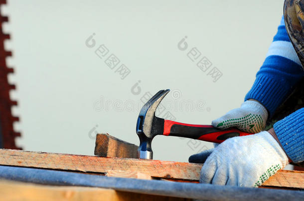 建筑屋顶。 工人在屋顶上钉钉子。 漫游者用锤子把钉子钉进新的屋顶梁里。 建筑钉子