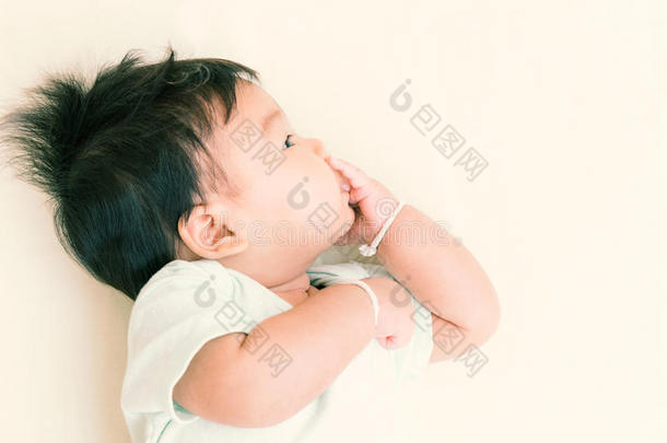 可爱的亚洲婴儿在床上吮吸。 这是生长发育行为。 （复古色调）