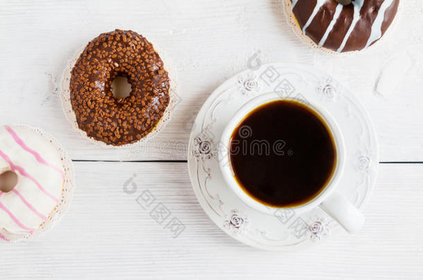 巧克力和釉面甜甜圈，粉红色，白色，棕色，白色木制<strong>桌子</strong>和一杯黑咖啡，<strong>俯视</strong>图