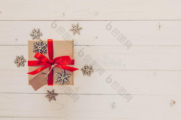 白色木制背景上的棕色礼品盒和雪花。 木制背景上的老式礼品盒。 木上有红色丝带的礼品盒