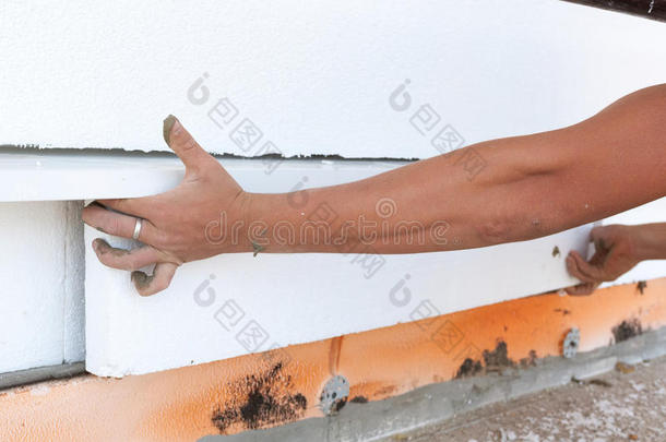 女<strong>职工</strong>将发泡胶板绝缘放置在房屋基础上。