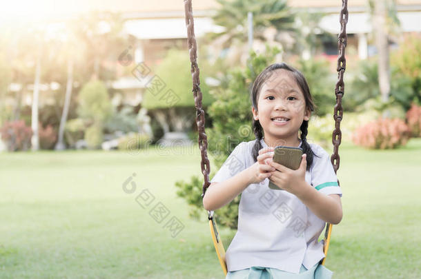 可爱的女孩在儿童游乐场展示智能手机
