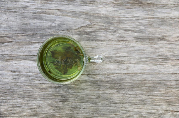 木制桌子上的清澈杯中的绿茶