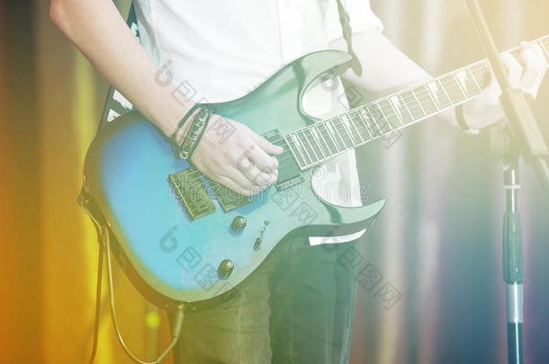 特写摇滚明星在舞台上玩电吉他。 穿着白色衬衫的男吉他手