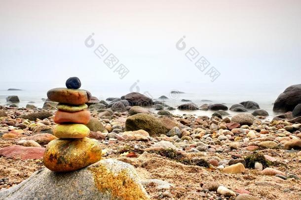 平衡的石金字塔在海边，波浪在背景。 五颜六色的<strong>扁平</strong>石头