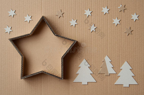 圣诞礼物盒的形状是一颗<strong>星星</strong>，<strong>周</strong>围是装饰品，在纸板背景上