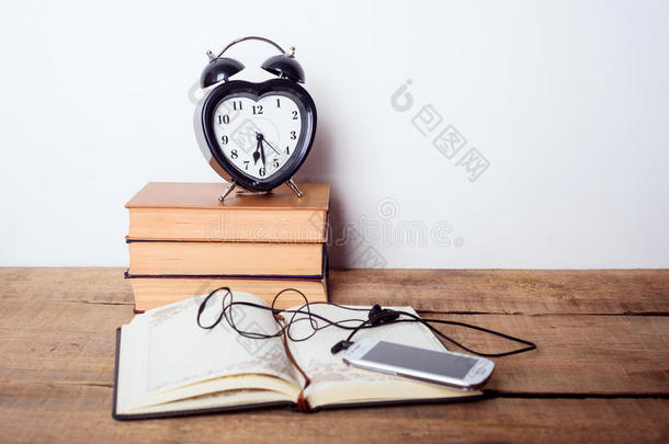 书，闹钟，记事本，木制背景上的手机