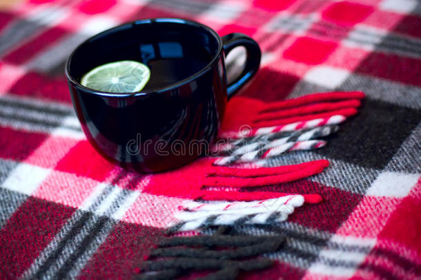 黑色杯子，茶和柠檬站在温暖的红色格子格子格子上