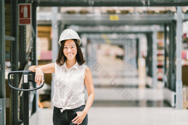 美丽的年轻亚洲工程师或技术人员微笑，仓库或工厂模糊的背景，行业或物流概念