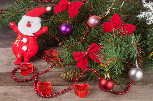 圣诞节的冷杉树枝组成，装饰有蝴蝶结和球，圣诞老人在木制背景上