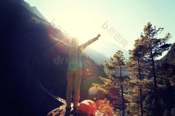 <strong>欢呼的</strong>年轻女子徒步旅行者张开双臂迎接日出