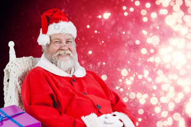 圣诞老人坐在椅子上，带着一袋圣诞礼物的图像