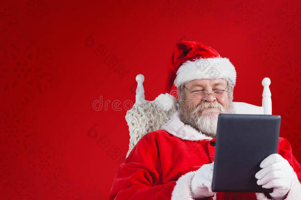 圣诞老人在扶手椅上拿着数字平板电脑的特写照片