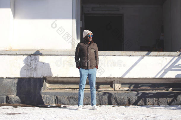 时尚时尚的年轻非洲男子站在夹克与针织帽，冬季街头风格