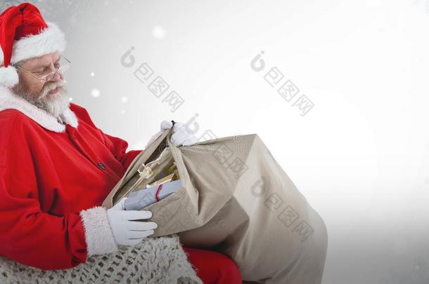 圣诞老人坐在椅子上拿着礼物在麻袋里的复合形象