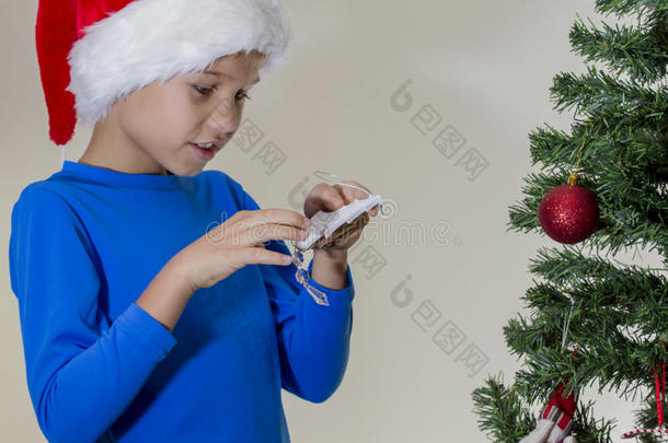 男孩在圣诞帽附近的圣诞树与圣诞节玩具