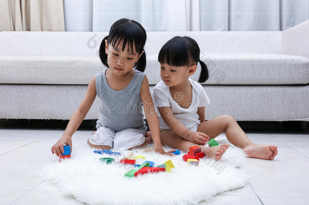 亚洲的中国小姐妹在地板上玩积木