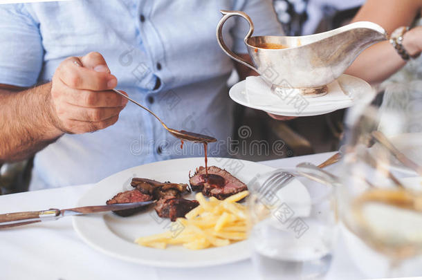 厨师在餐厅里把食物镀上，然后把肉汁或酱汁倒在肉上，然后再给顾客端上菜
