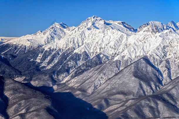 美丽的高山冬季风景的主要高加索山脉与雪峰在蓝天背景