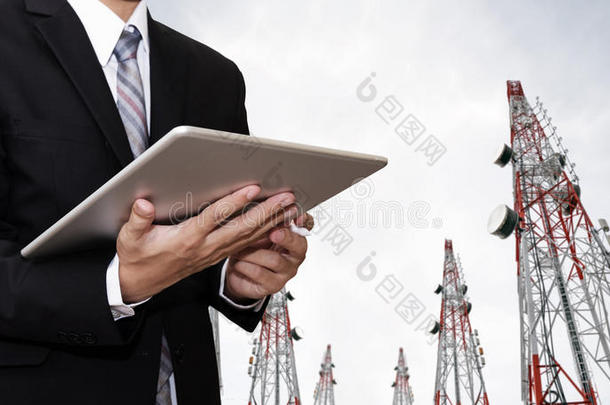 商人在数字平板电脑上工作，与卫星碟电信网络在电信塔上工作