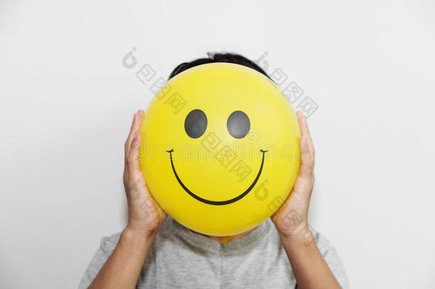 一个男人拿着一个黄色的气球，微笑着面对表情而不是头。 隐藏一些不好的感觉，保持微笑