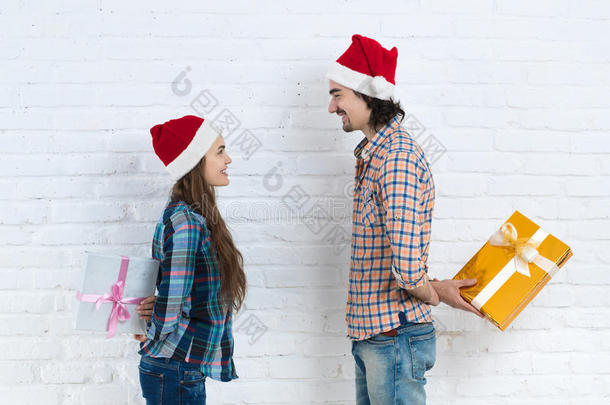 圣诞假期快乐夫妇拿着惊喜礼物盒戴着新年圣诞帽，男人和女人微笑