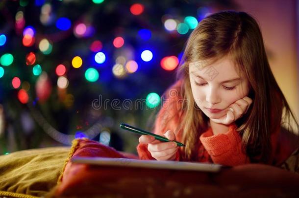 可爱的小女孩在圣诞节的壁炉旁给圣诞老人写了<strong>一封信</strong>