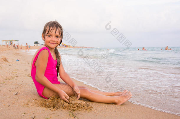五岁的女孩坐在海滩海边