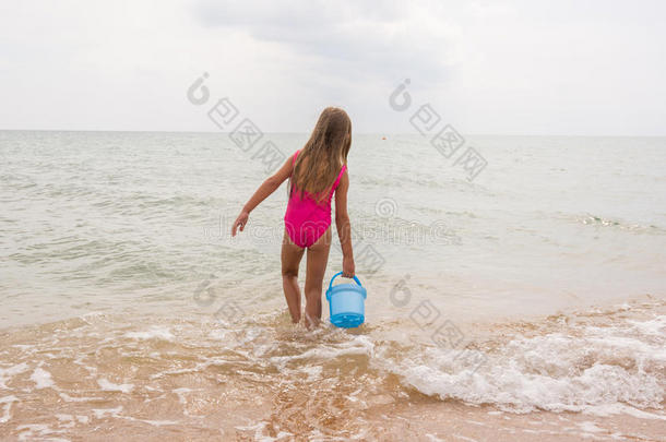 五岁的女孩在海里捡一桶水